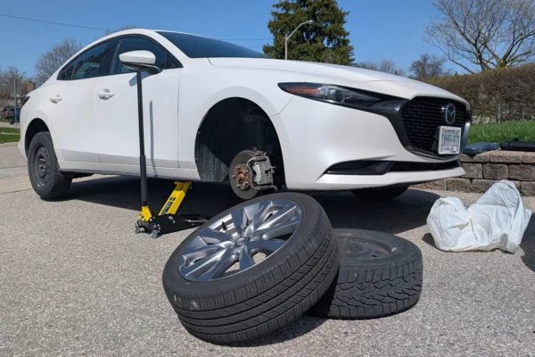 Car in the driveway having its summer tires removed and winter tires fitted.