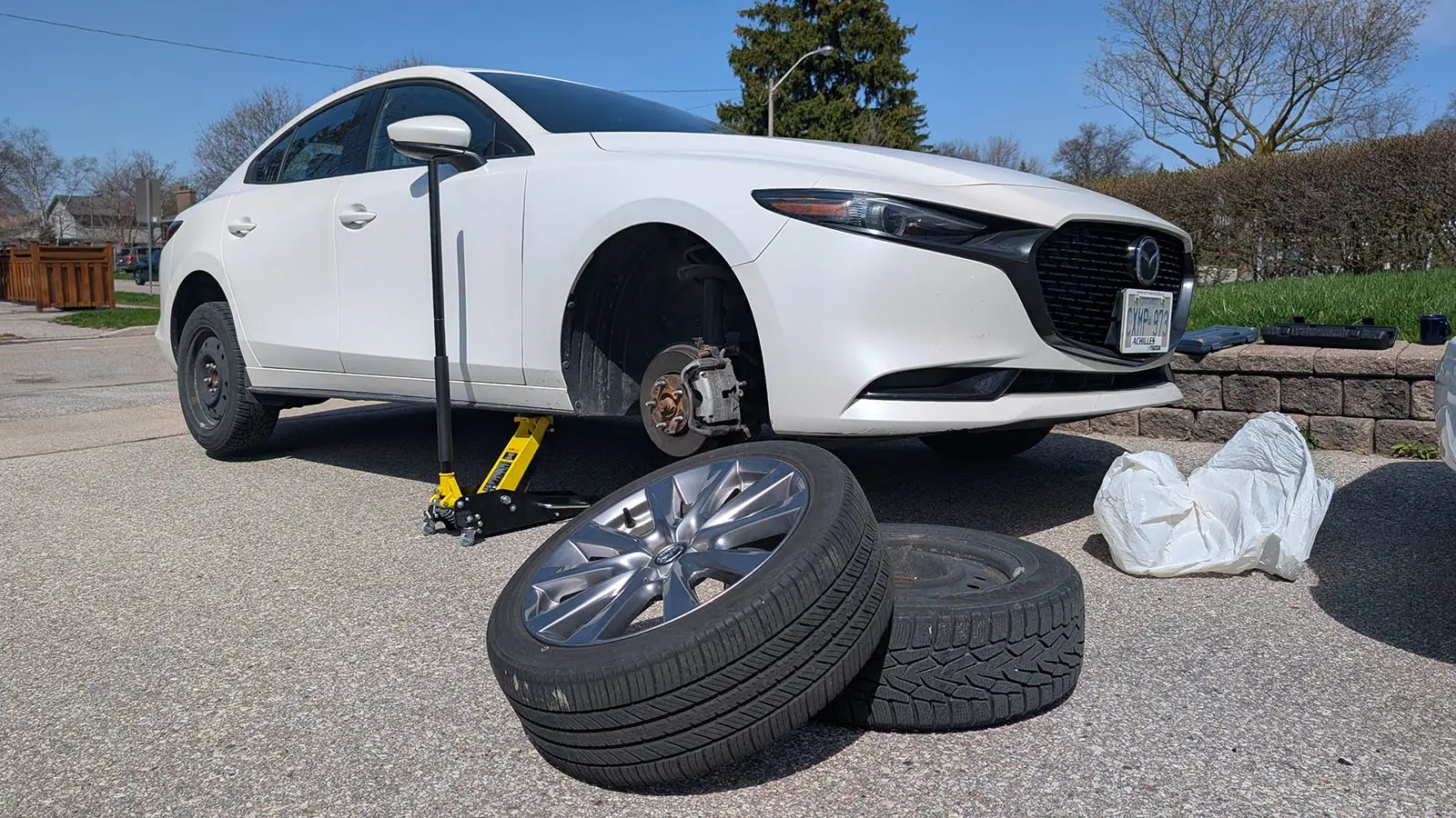 Car in the driveway having its summer tires removed and winter tires fitted.